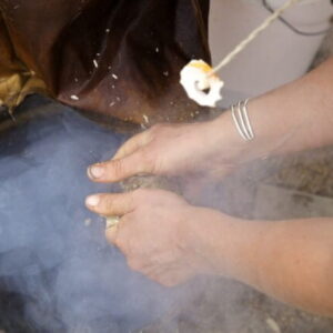 adding punky wood to a fire for brain tanning a deer hide