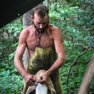 man scraping off the membrane of a hide for tanning