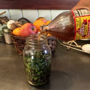 pouring vinegar over herbs in a bottle