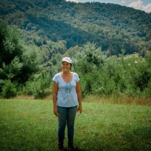 woman standing a field with mountains living off the land