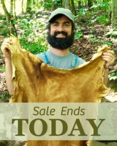 man holding up a finished brain tanned buckskin