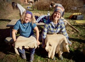 two women stretching hides during brain tanning