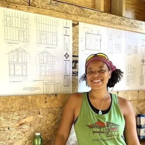 Woman poses in front of plans during tiny house workshop