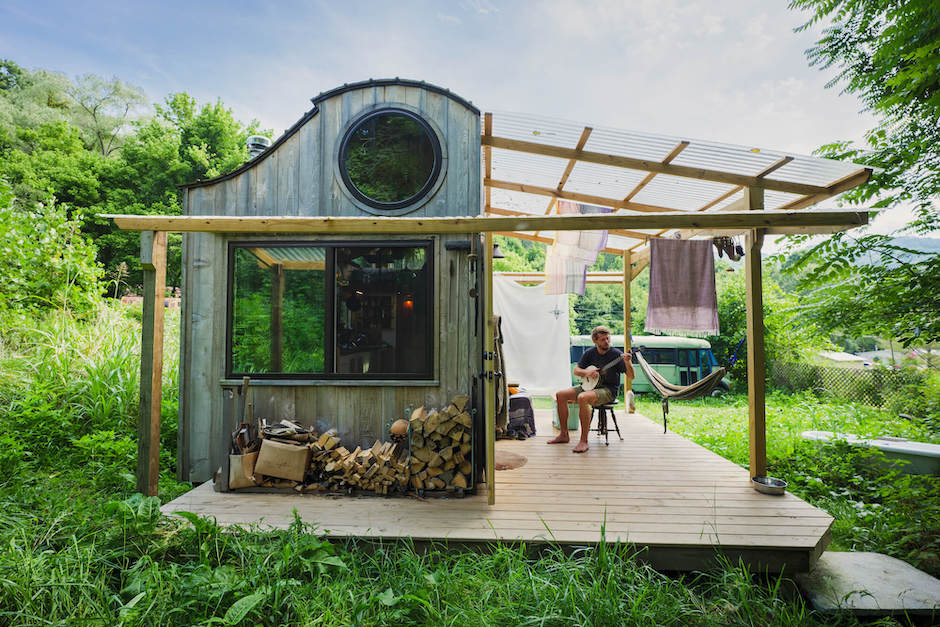 Man plays banjo in front of tiny house