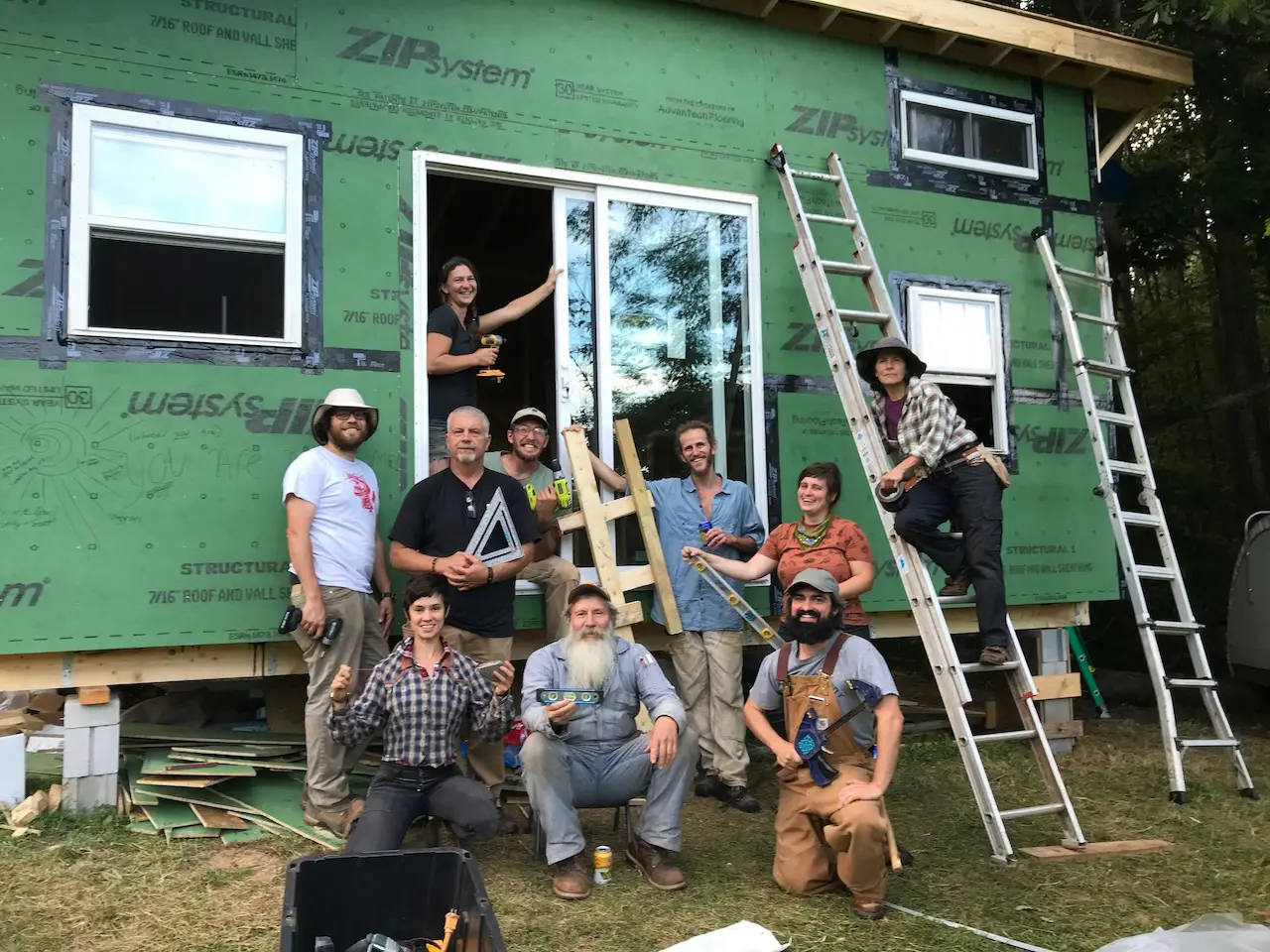 https://www.wildabundance.net/wp-content/uploads/2022/05/students-and-barron-posing-in-front-of-tiny-house.jpeg.webp