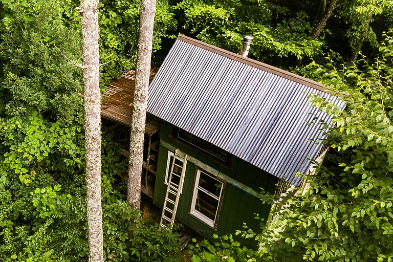 A DIY tiny house nestled in the woods is seen from above