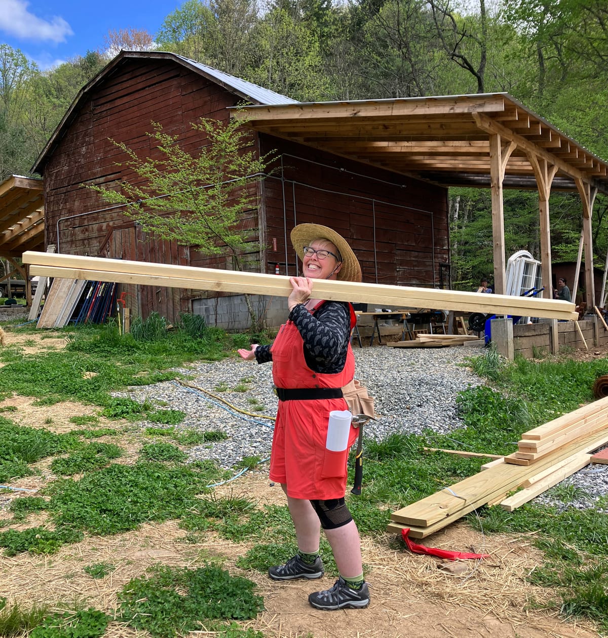 A woman carrying a board to a buildling project during the 4 month hands-on carpentry training program at Wild Abundance