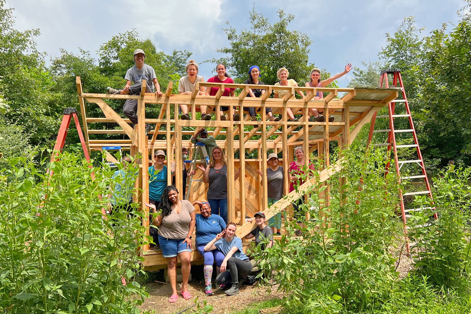 An advanced women's carpentry class smiles from the shed structure they are building in class at whild abundance