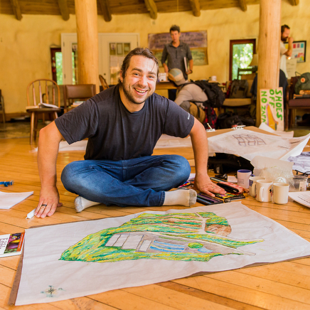 male permaculture design student smiles up from working on his design to earn his PDC at an in-person class at Wild Abundance