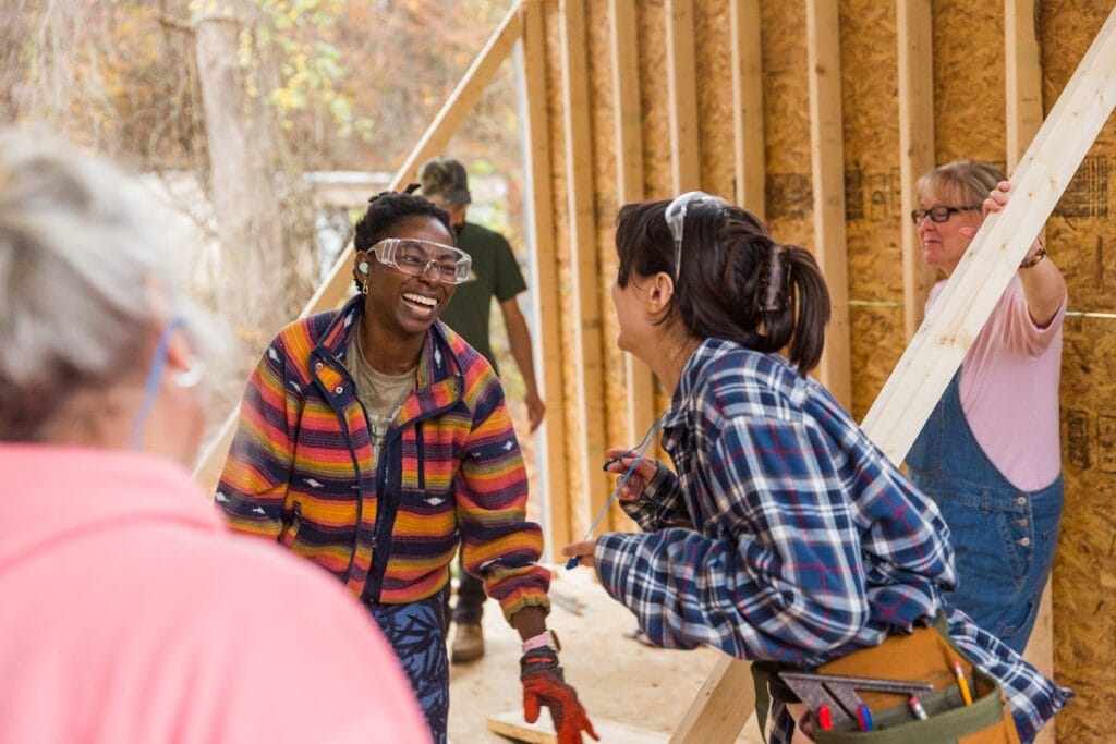 diverse students in a Tiny House building workshop smile and laugh together