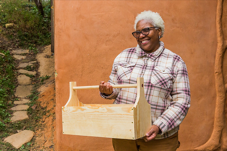 A student shows off her solo project at the end of a women's carpentry class, a 4 day workshop at Wild Abundance DIY skills school.